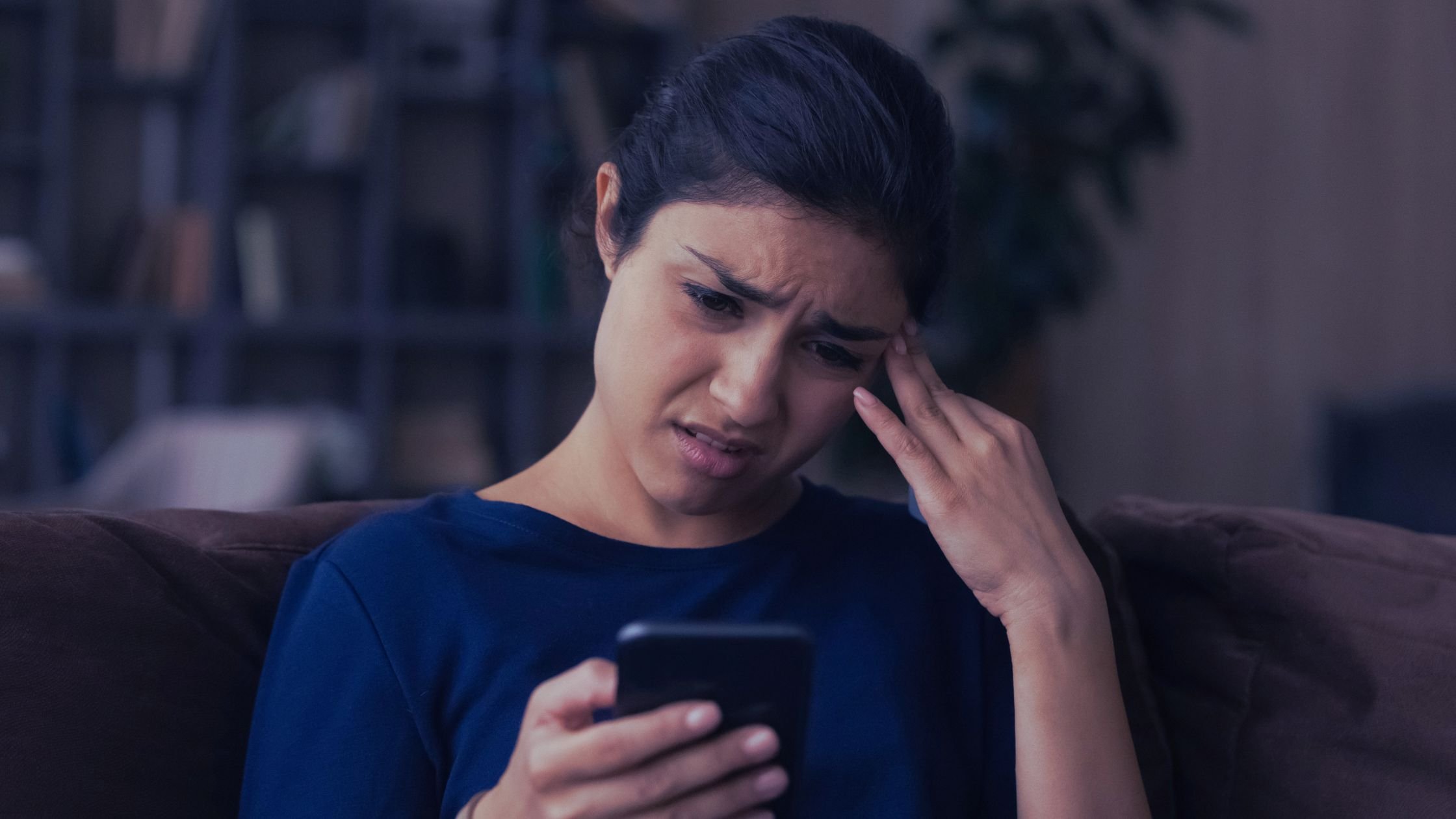 ## Alt Text  Frustrated woman struggling to navigate a confusing website while looking at her phone at home.