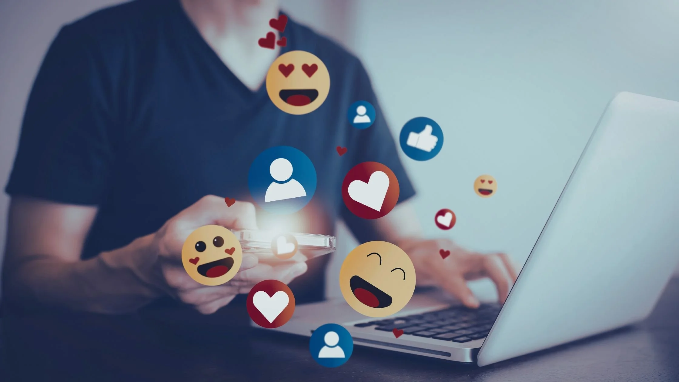 Person using social media on a smartphone and laptop with engagement icons, representing social media marketing and online audience engagement.