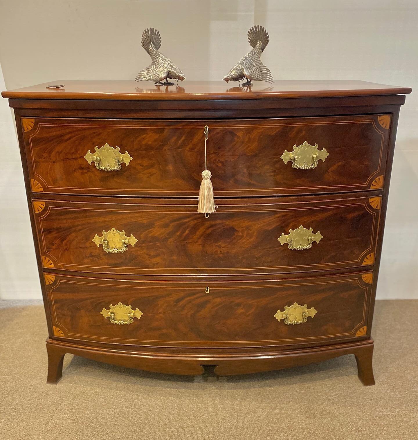 Just Arrived ~ SOLD ~ An attractive 19th century flame mahogany bow fronted chest of three drawers, decoratively inlayed, brass drop handles all on splayed feet.