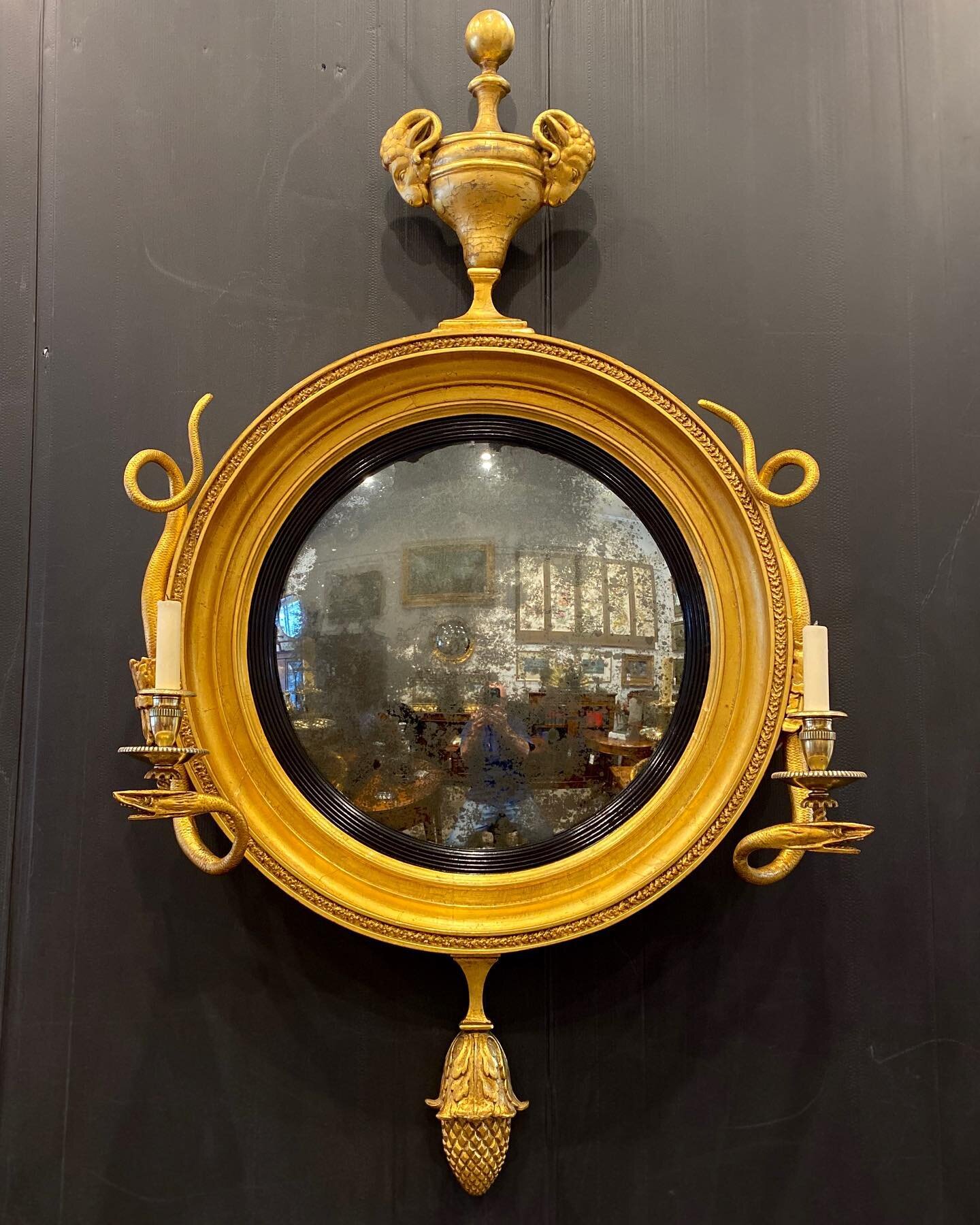 Our restoration of this superb 19th century gilt convex mirror, highly decorated with ram heads and snake candelabras, ebonised reeded slip and it&rsquo;s original mercury lined mirror.