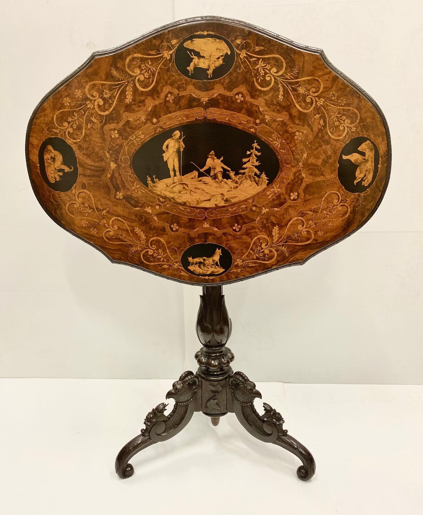 A beautiful 19th century walnut Black Forest inlay table, top tilts back to display images of animals and hunting scene, magnificently carved tripod base also depicting animals.