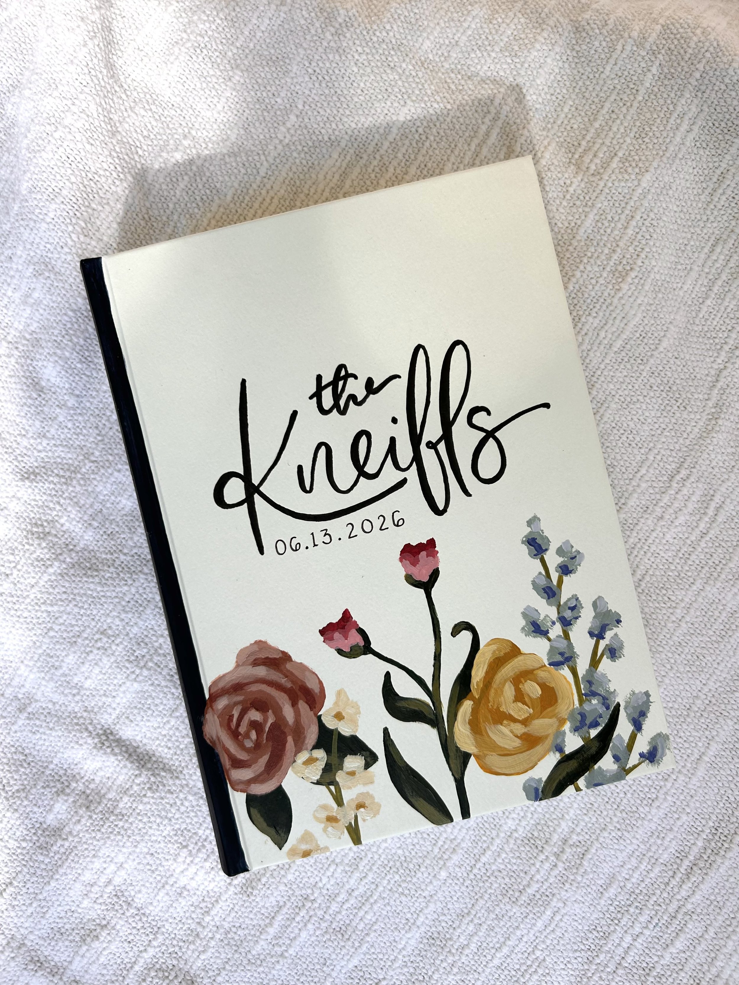 A closed wedding planner with floral illustrations and the date 06.13.2026