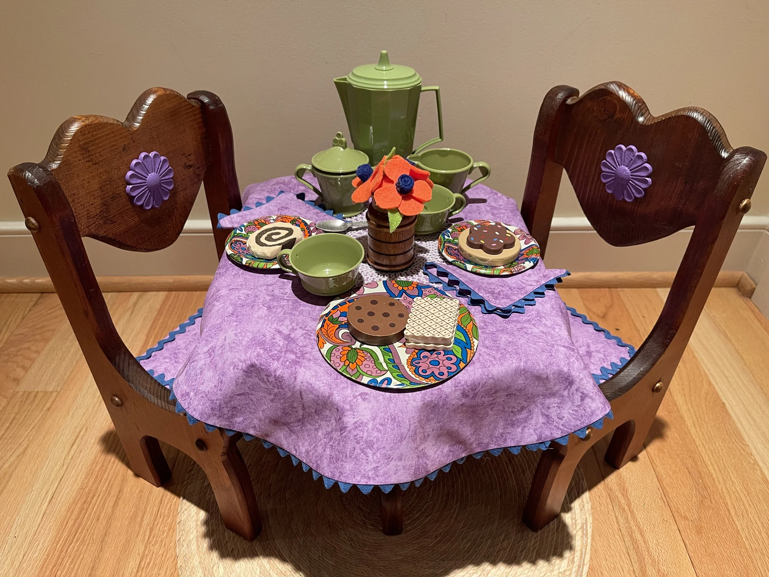 This set is scaled for a young child. The tea set and cookies are safely sized. This would fit some stuffed animals or dolls. Flowers are felt and vase is wood.  $78