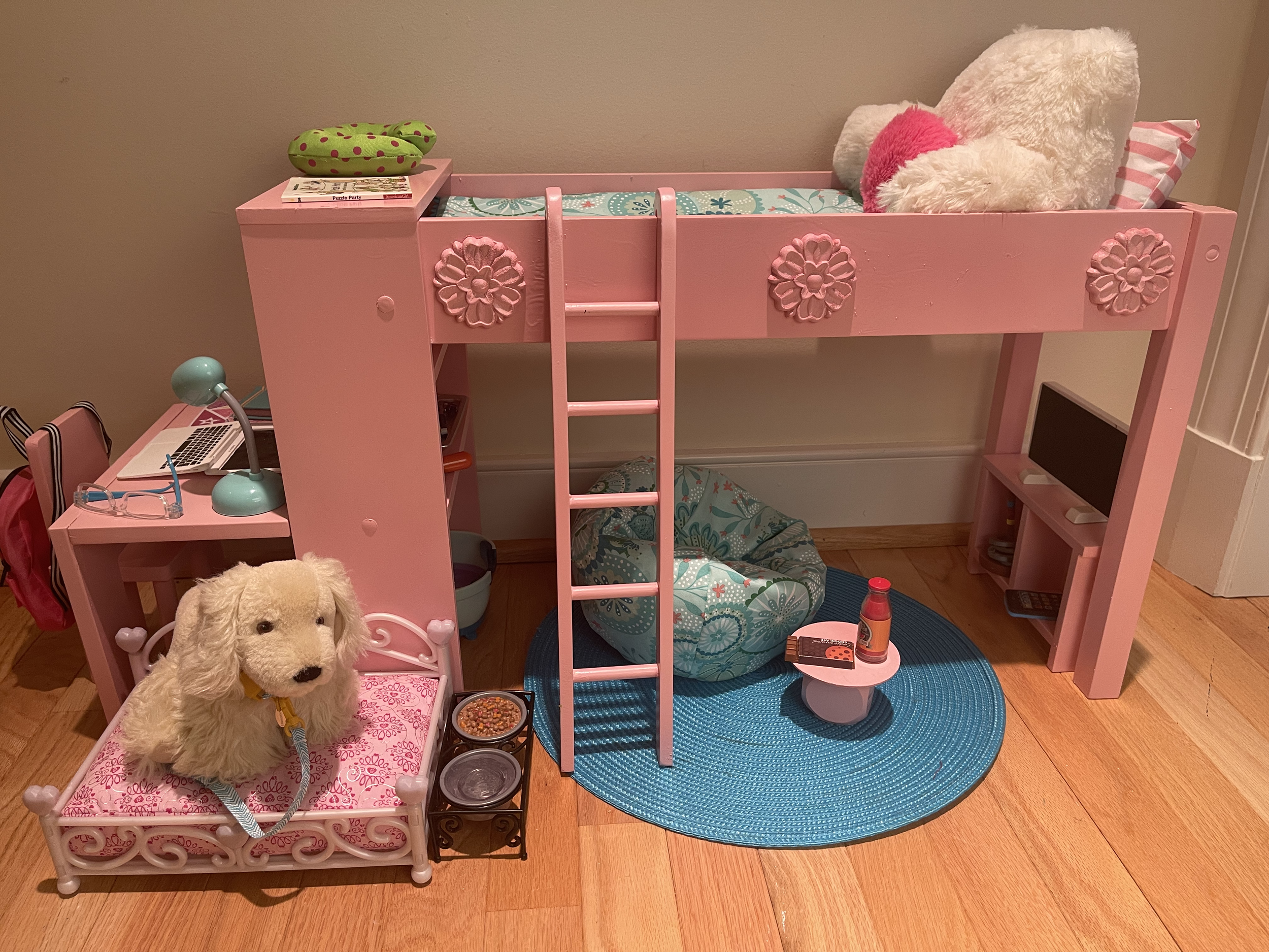 Loft bed features all bedding. included are a desk complete with supplies and a backpack. Also, a vanity area with a set of supplies. There is a bean bag chair and snack table for the tv-watching, music-listening area. Included also are a dog and his