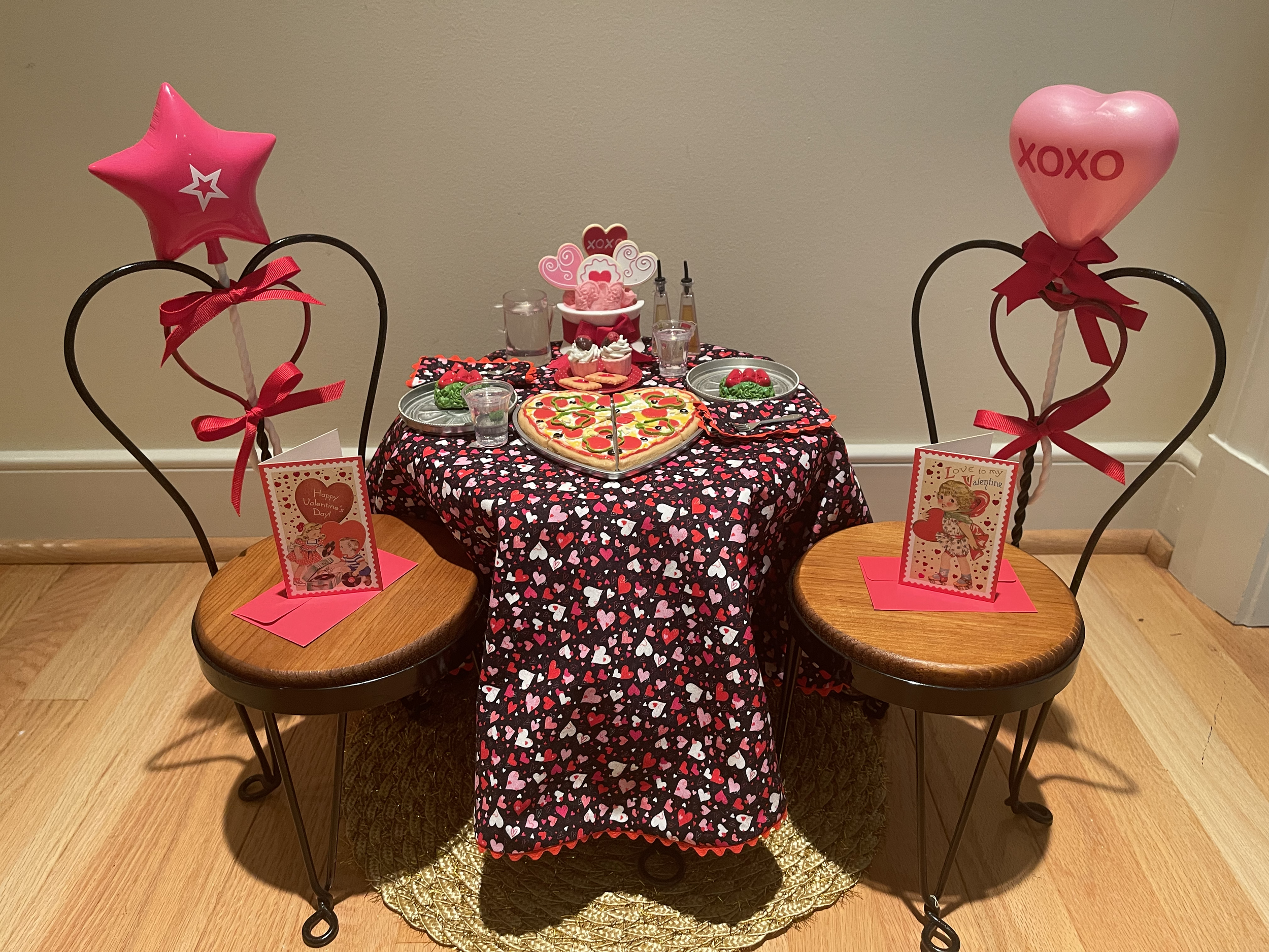 Valentine's Day pizza dinner features heart-shaped pizza, salads, desserts, valentines, balloons. Tablecloth and napkins reverse to non-holiday fabric. $78