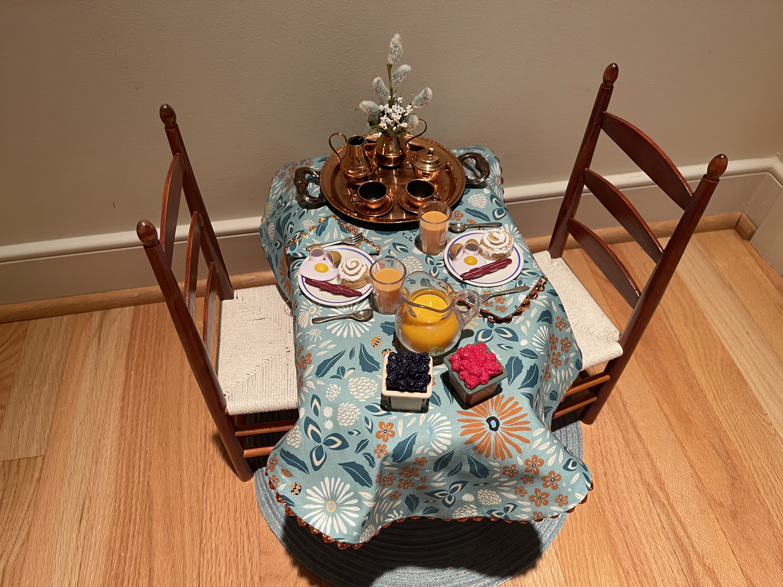 This breakfast table includes a complete meal, orange juice, and a vintage copper tea set. $76