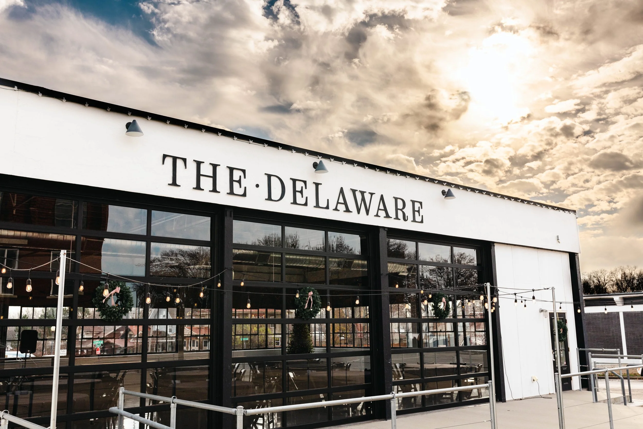 Exterior of The Delaware building with large “THE DELAWARE” sign and windows.