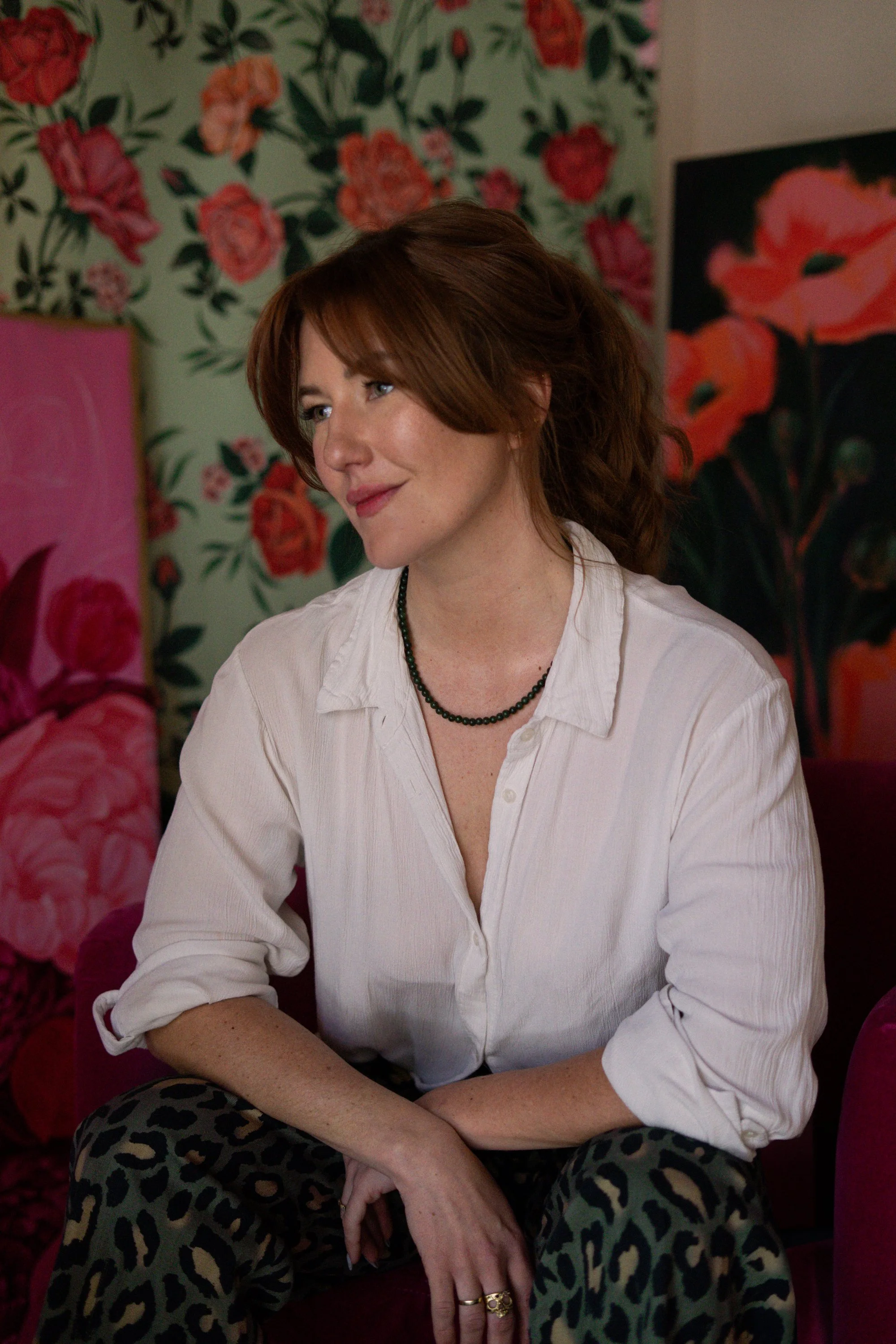 Portrait image of Maggie Enterrios in front of her artwork,, illustrator and botanical packaging artist