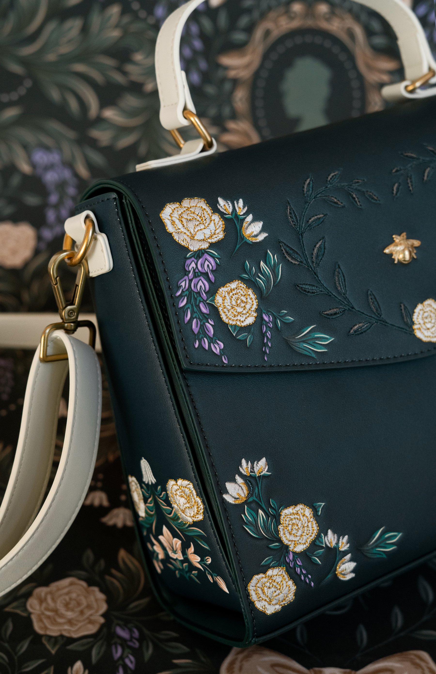 Pattern illustration by Maggie Enterrios for Bridgerton Loungefly limited edition collection. Image of green embroidered purse on intricate illustrated damask floral background