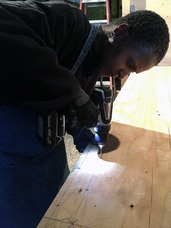 Dominique Moody holding a drill and working on the nomad frame