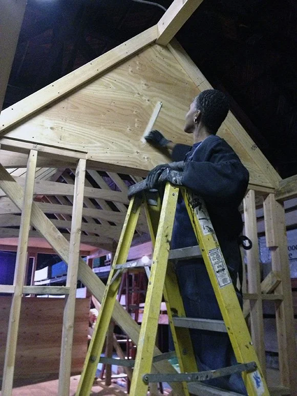 Dominique Moody up on a ladder, working on the nomad frame