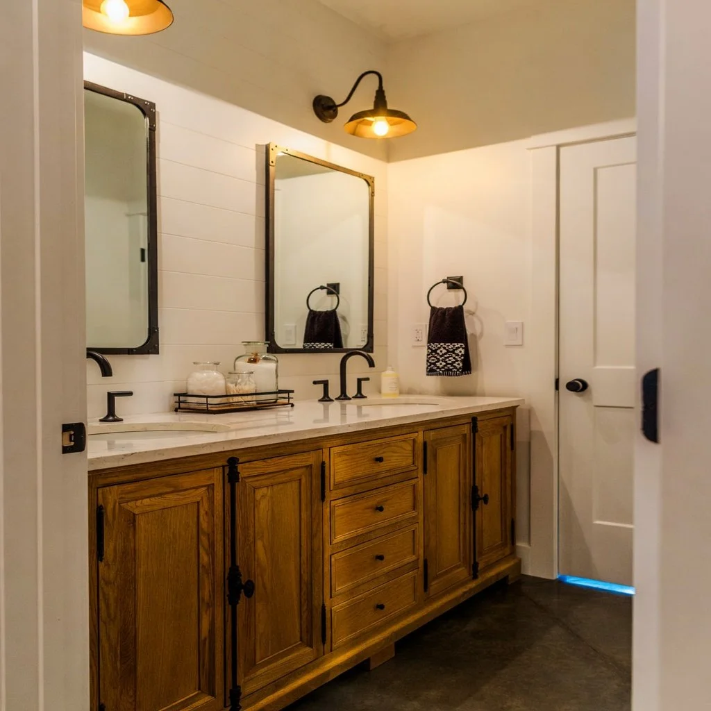 Custom home farmhouse bathroom with double vanity, wood cabinetry and framed mirrors