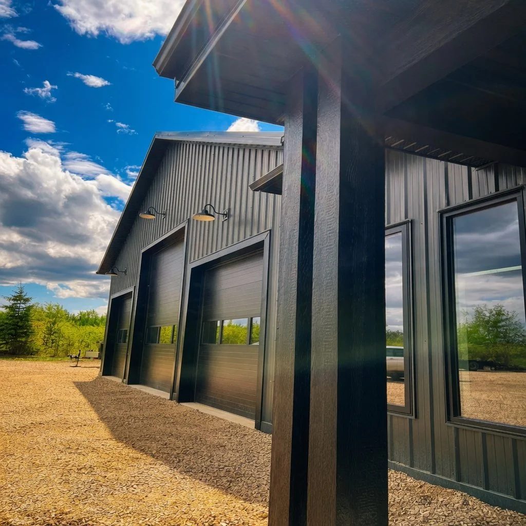 Custom commercial shop building exterior with black metal cladding and overhead doors