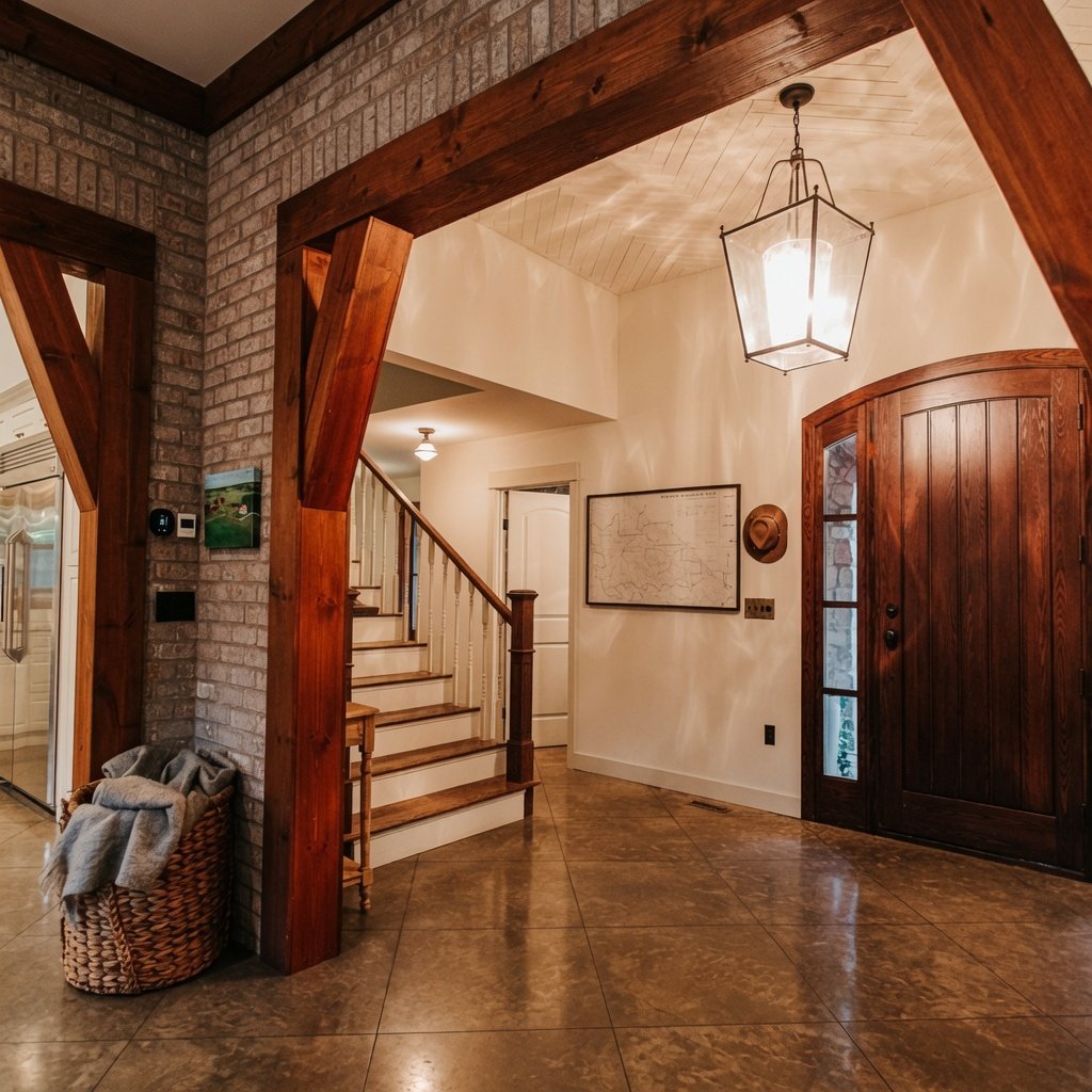 Custom home entry foyer with exposed brick wall, staircase and lantern pendant