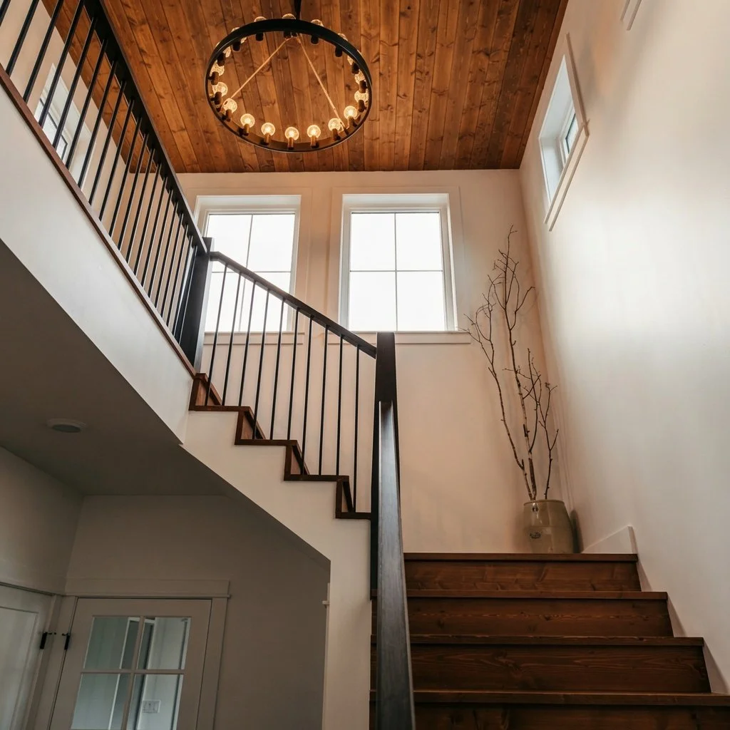 Custom home two-storey staircase with wood treads, iron railing and chandelier