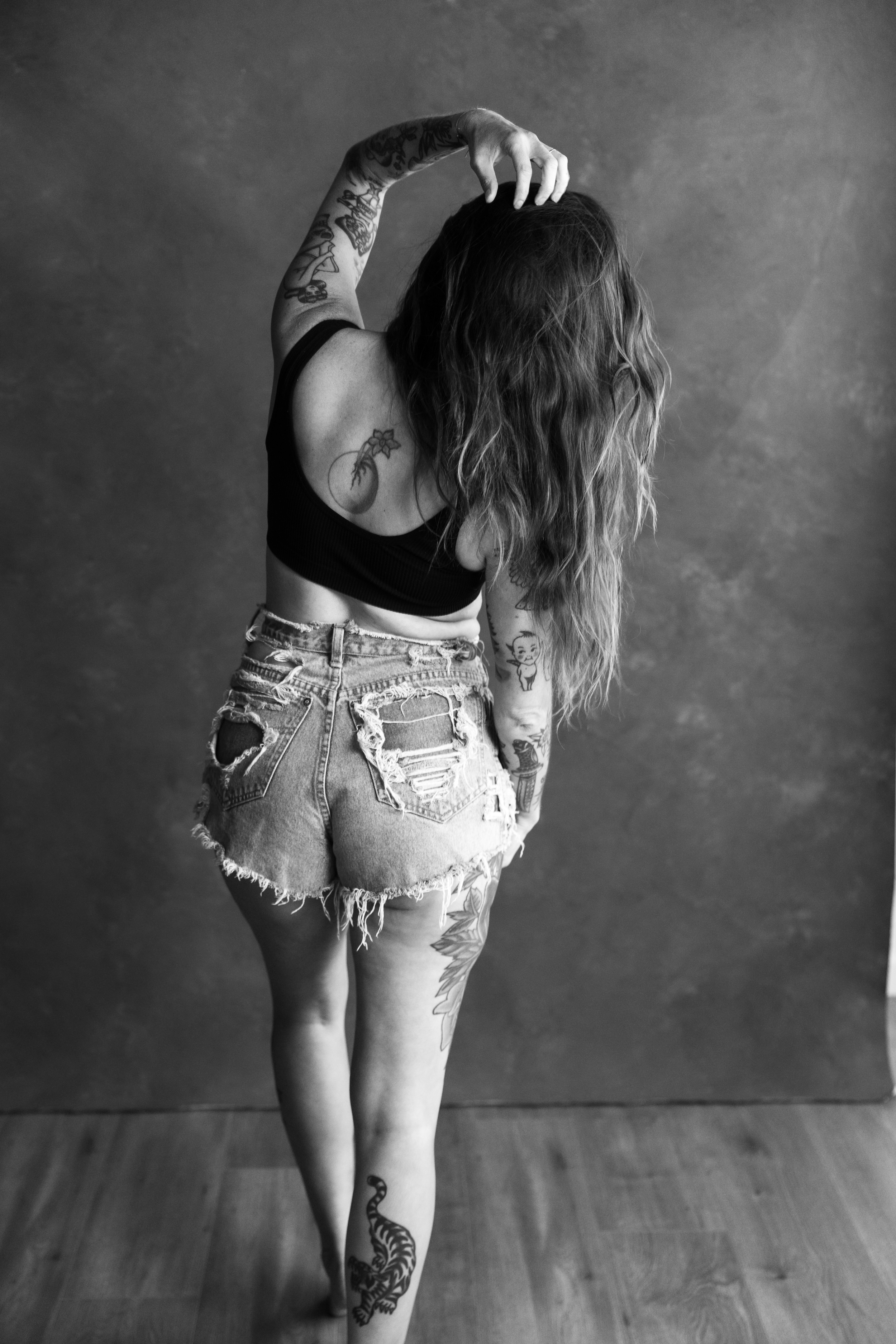 Black and white self-love portrait of a tattooed woman with arms raised, captured in a Just BE Experience session in San Luis Obispo County.