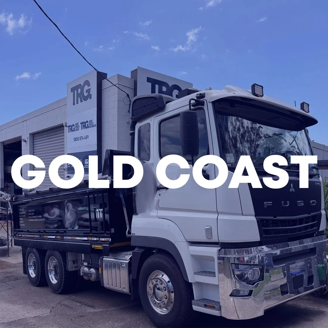 RV entering truck repair shop with 'Gold Coast' text above, sunny day.