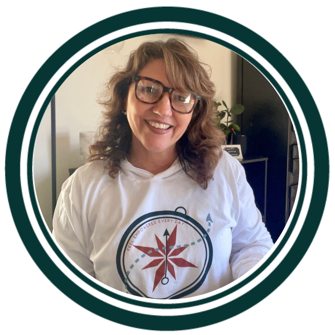 a woman with glasses smiling wearing a shirt with a compass that says feel empowered every day