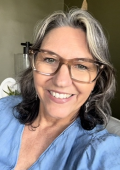 a smiling woman with glasses leaning in a chair in her office
