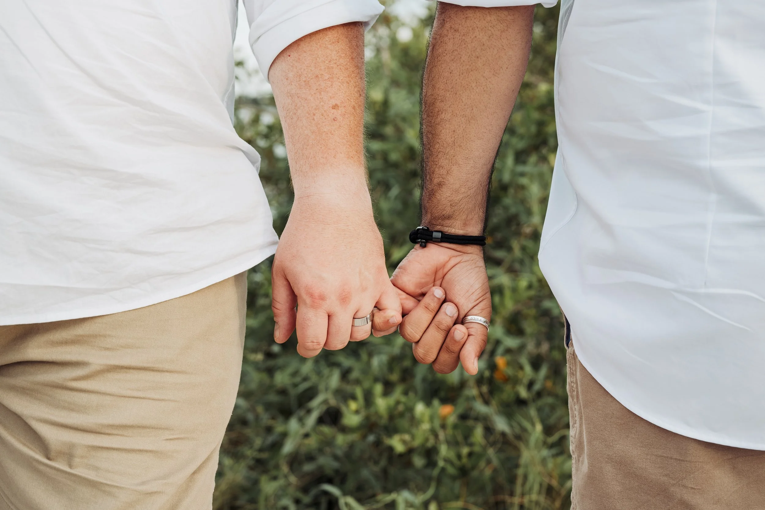 Two people holding hands outdoors, wearing casual clothing.