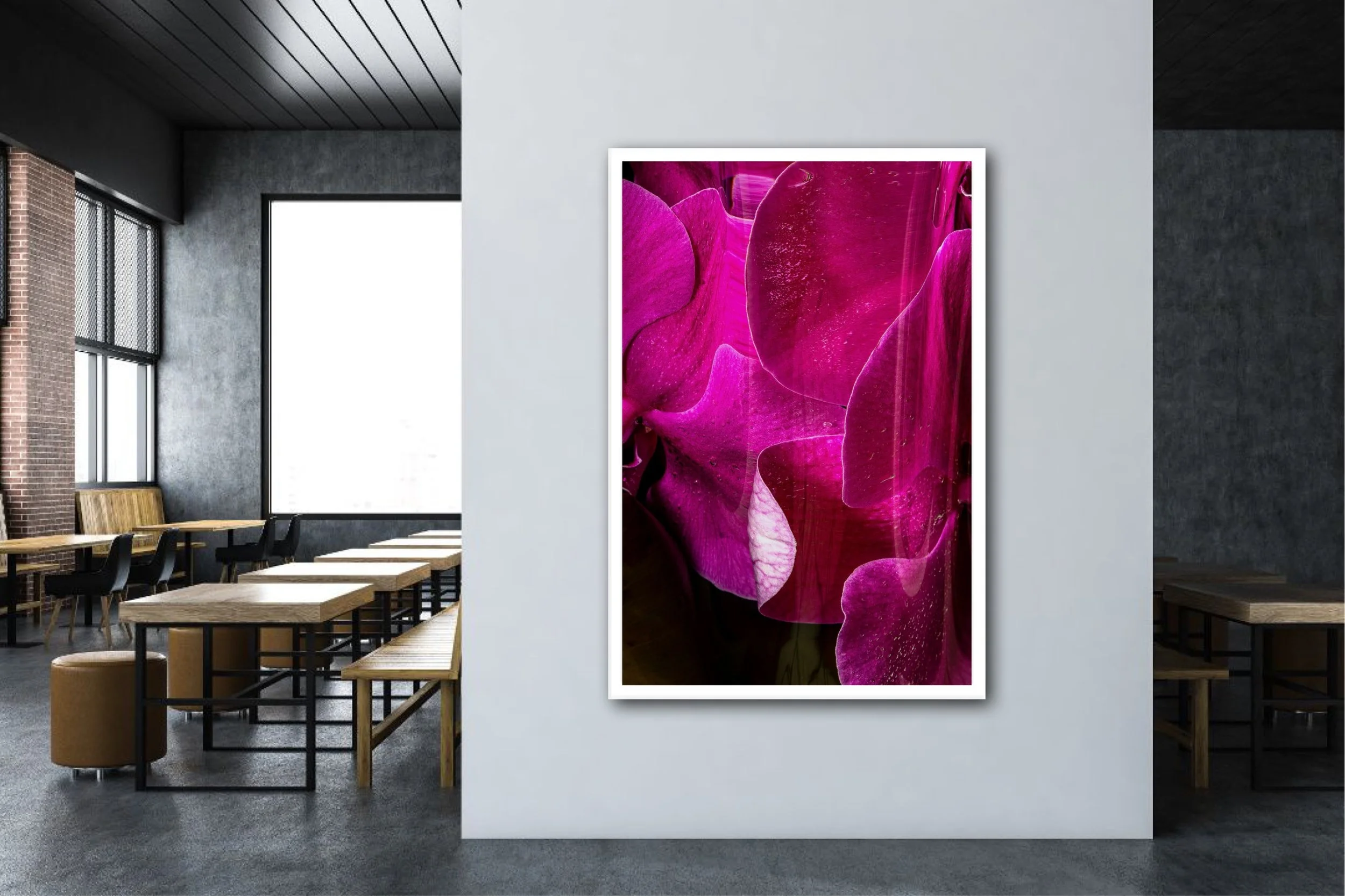 Interior of a modern art gallery with a large pink floral painting on a white wall. The gallery features high ceilings, large windows, minimalist wooden benches, and concrete and brick walls.