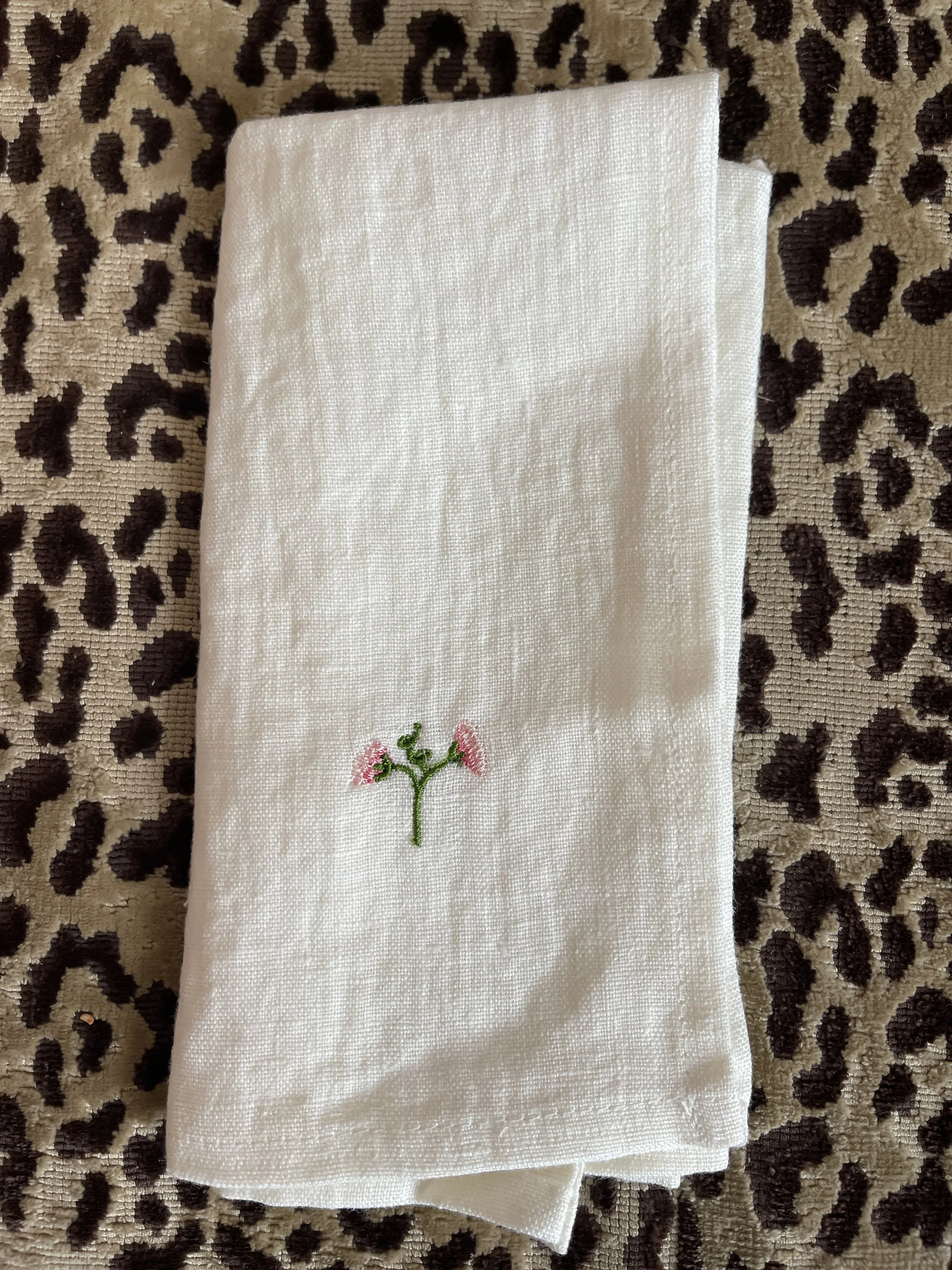 Embroidered sweet pea flowers on a white napkin