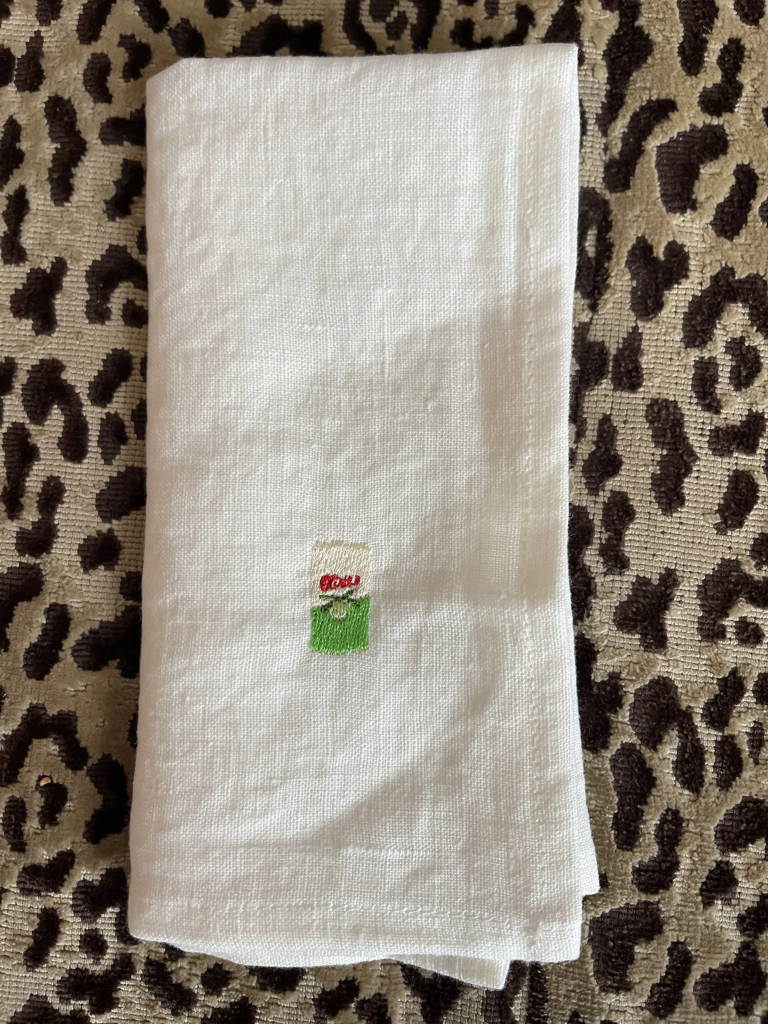Embroidered Perelló olive tin on a white napkin