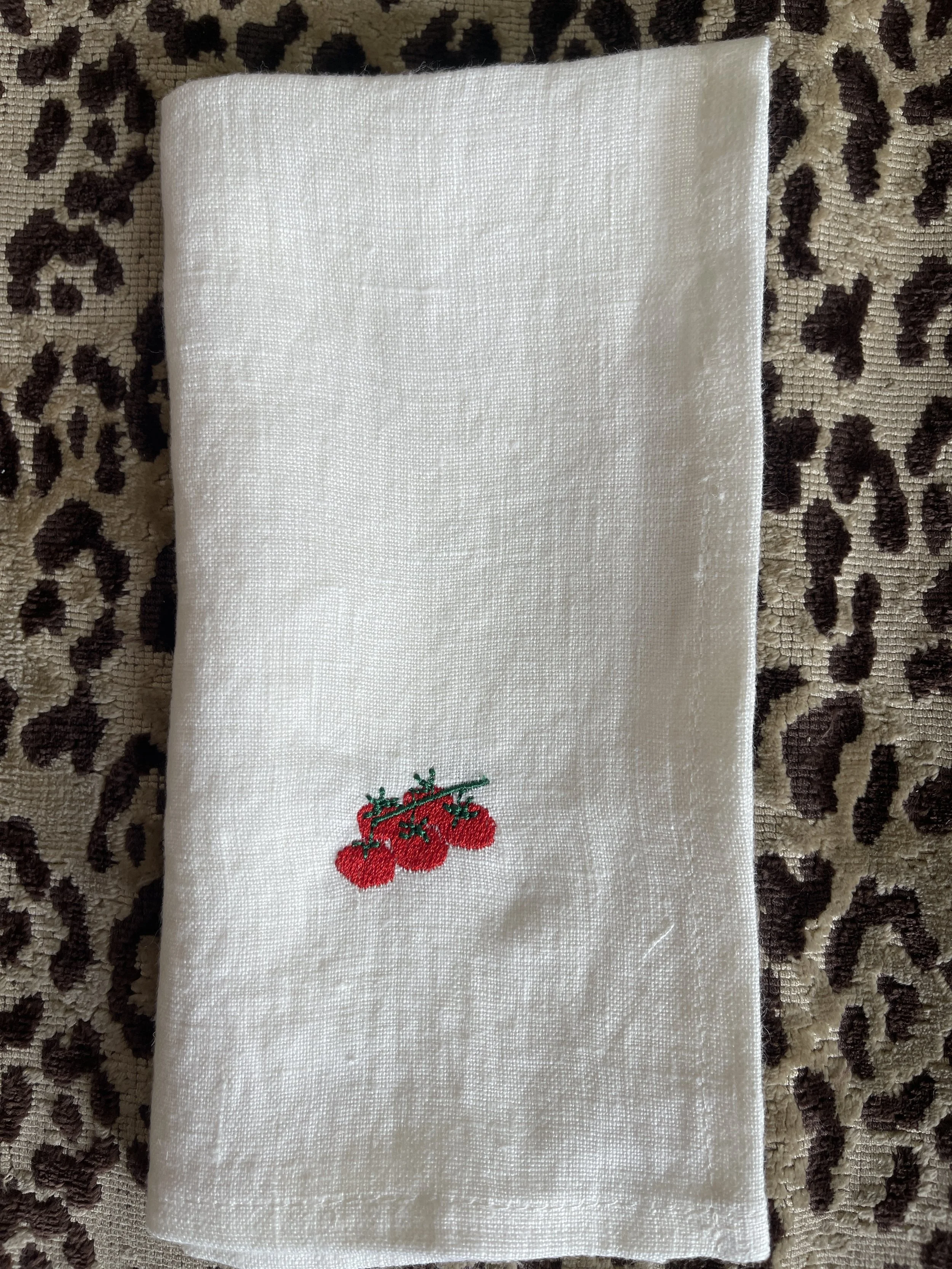 Embroidered tomatoes on the vine on a white napkin