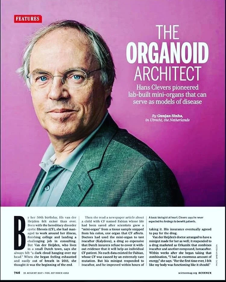Voorpagina van een wetenschappelijk tijdschrift met een foto van een man in een grijs pak tegen een roze achtergrond, met de titel 'The Organoid Architect' en een korte beschrijving over Hans Clever's pionierswerk met laboratorium-mini-organen.