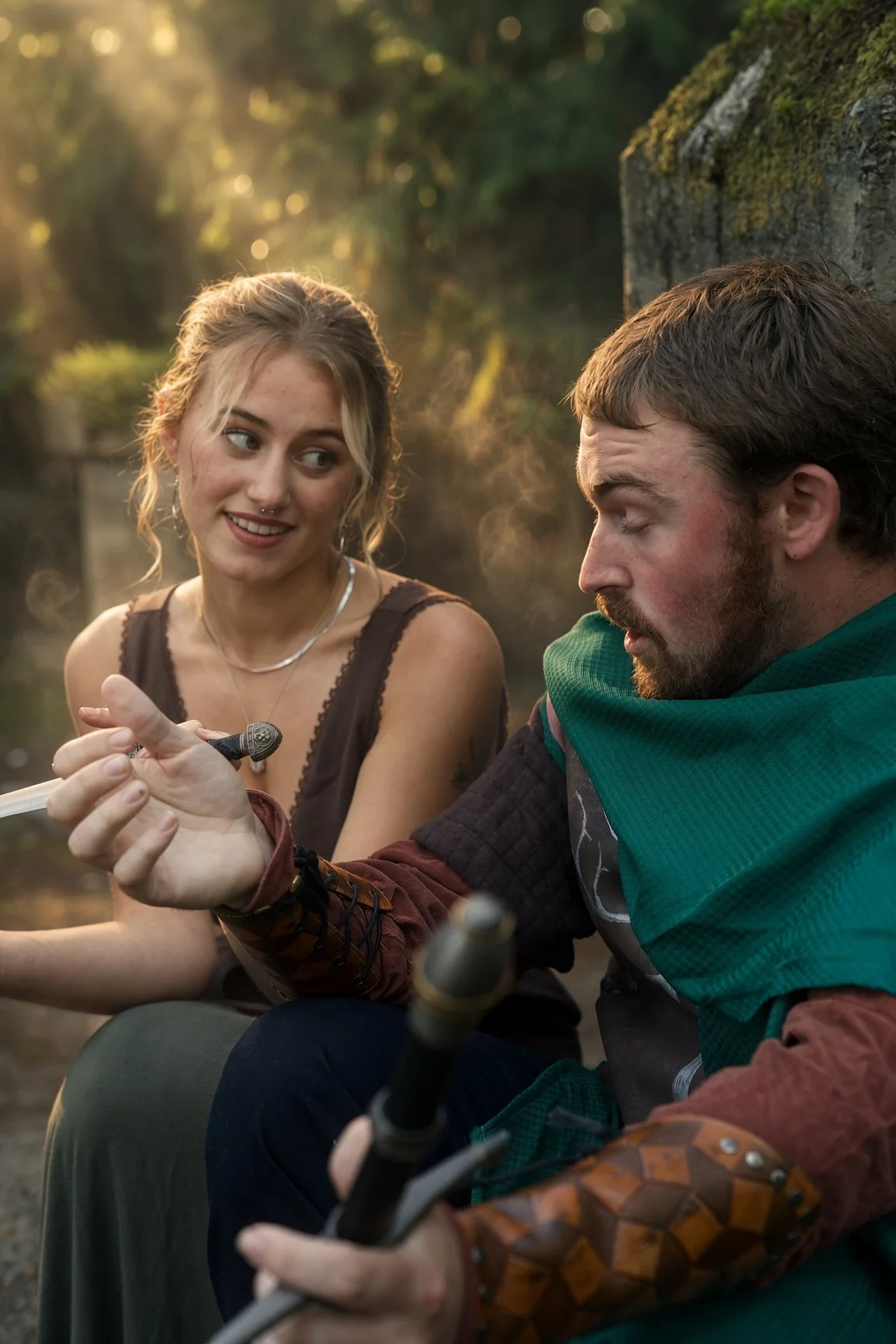 Two people sitting outdoors during sunset, one woman with blonde hair and a septum piercing, and one man with a beard and brown hair, both dressed in medieval or fantasy-inspired clothing, and holding a sword.