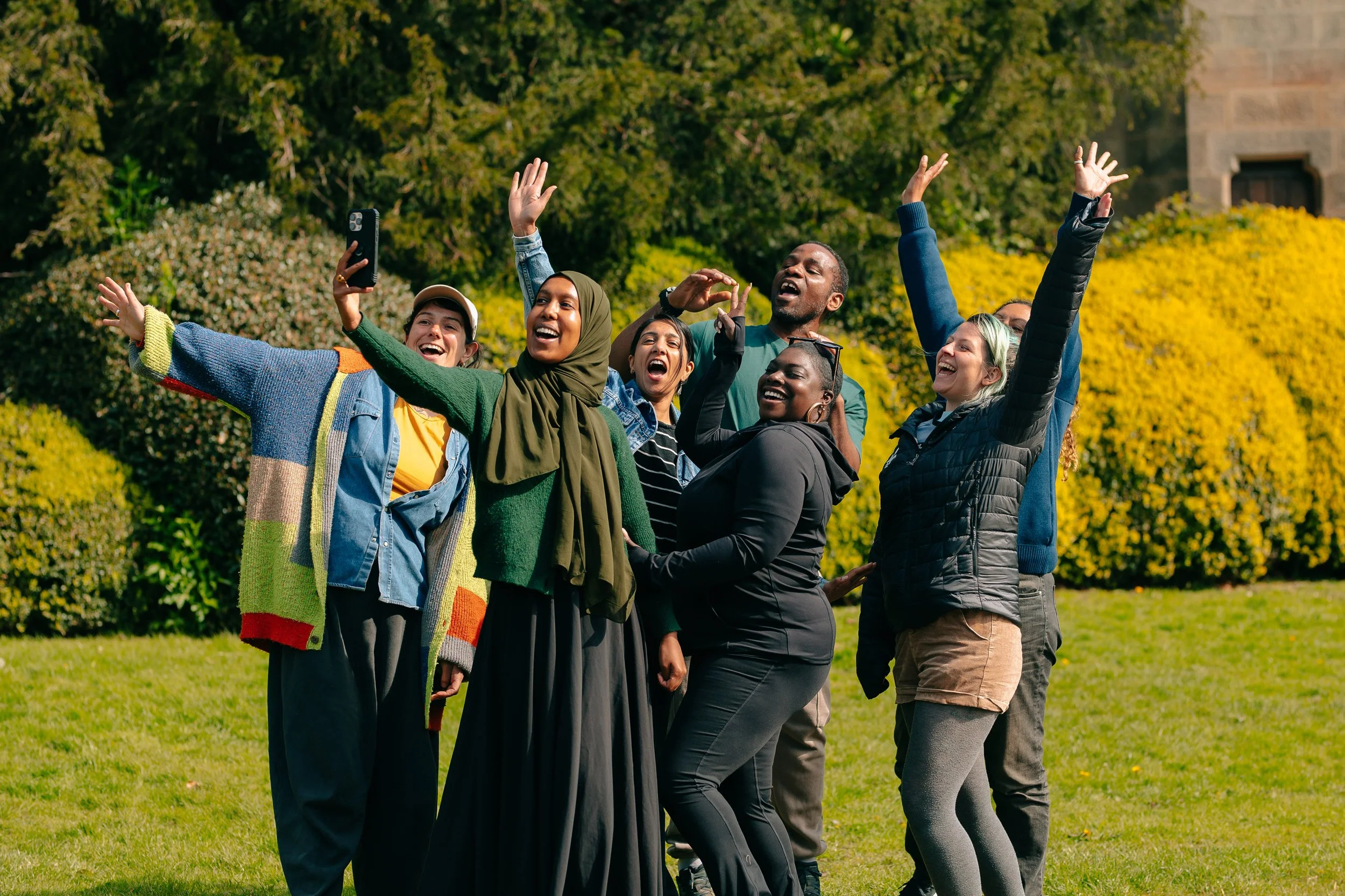 A group of people simile at the camera with their arms up
