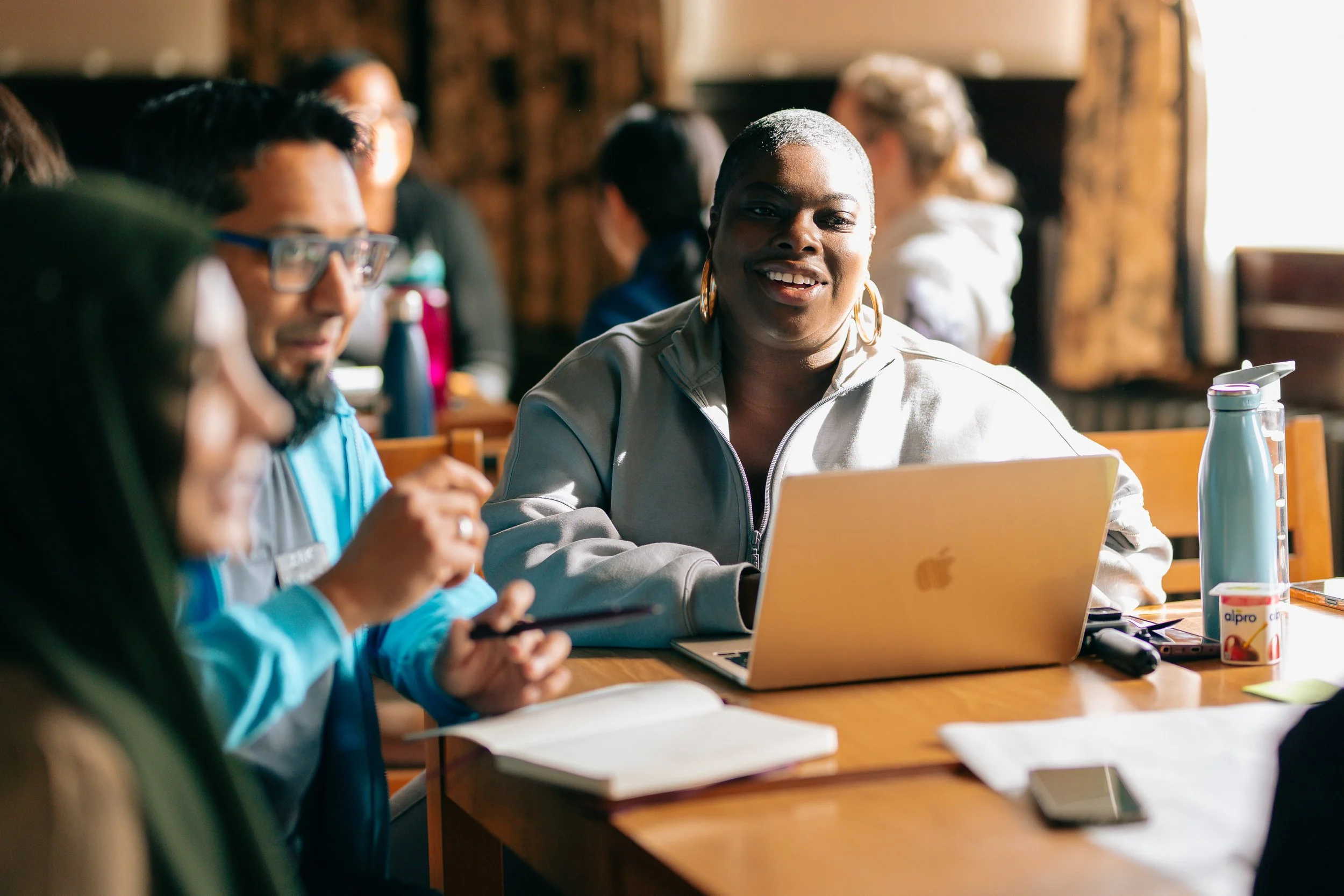 People taking notes, looking on a laptop and discussing round a table