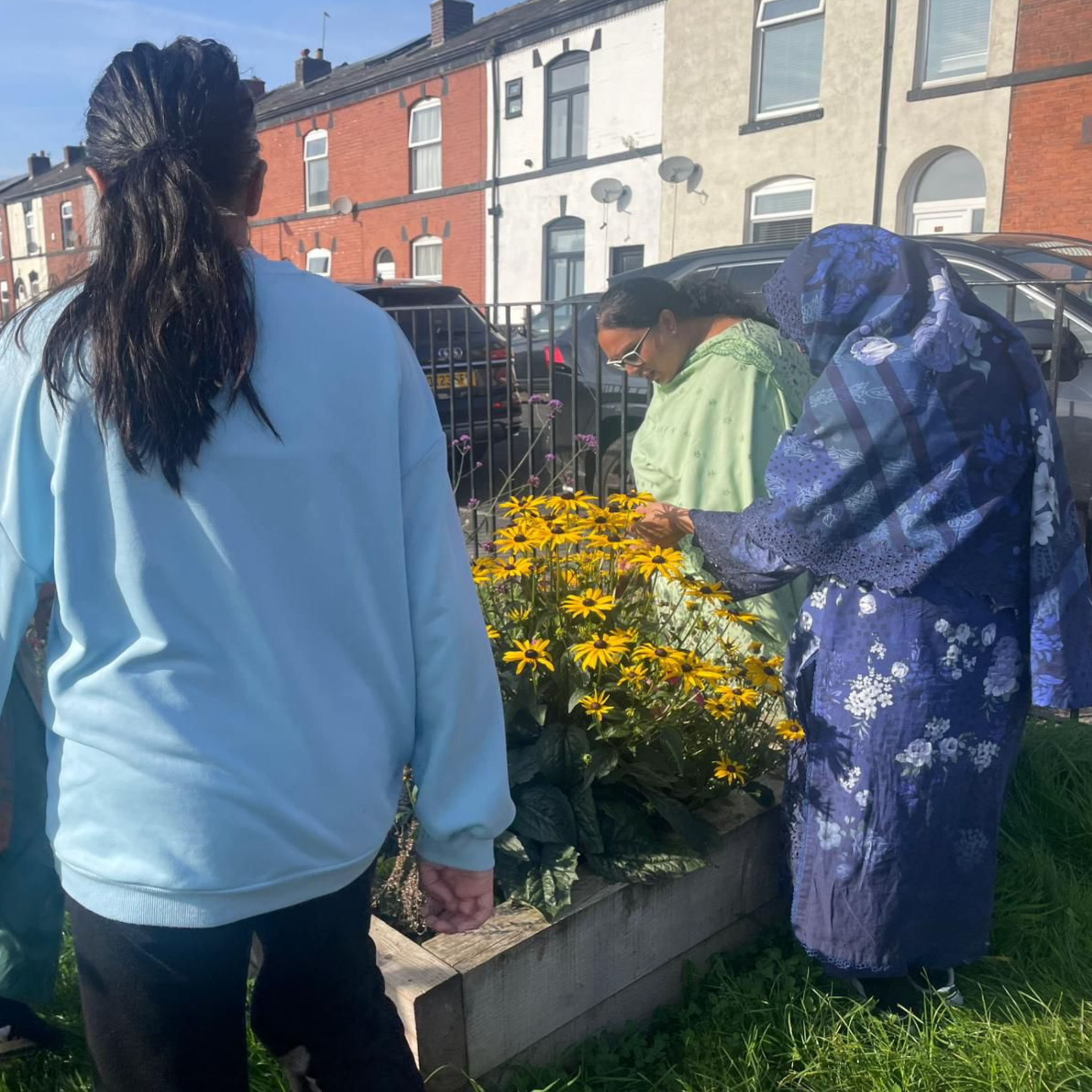 2 people looking at yellow flowers in a street garden