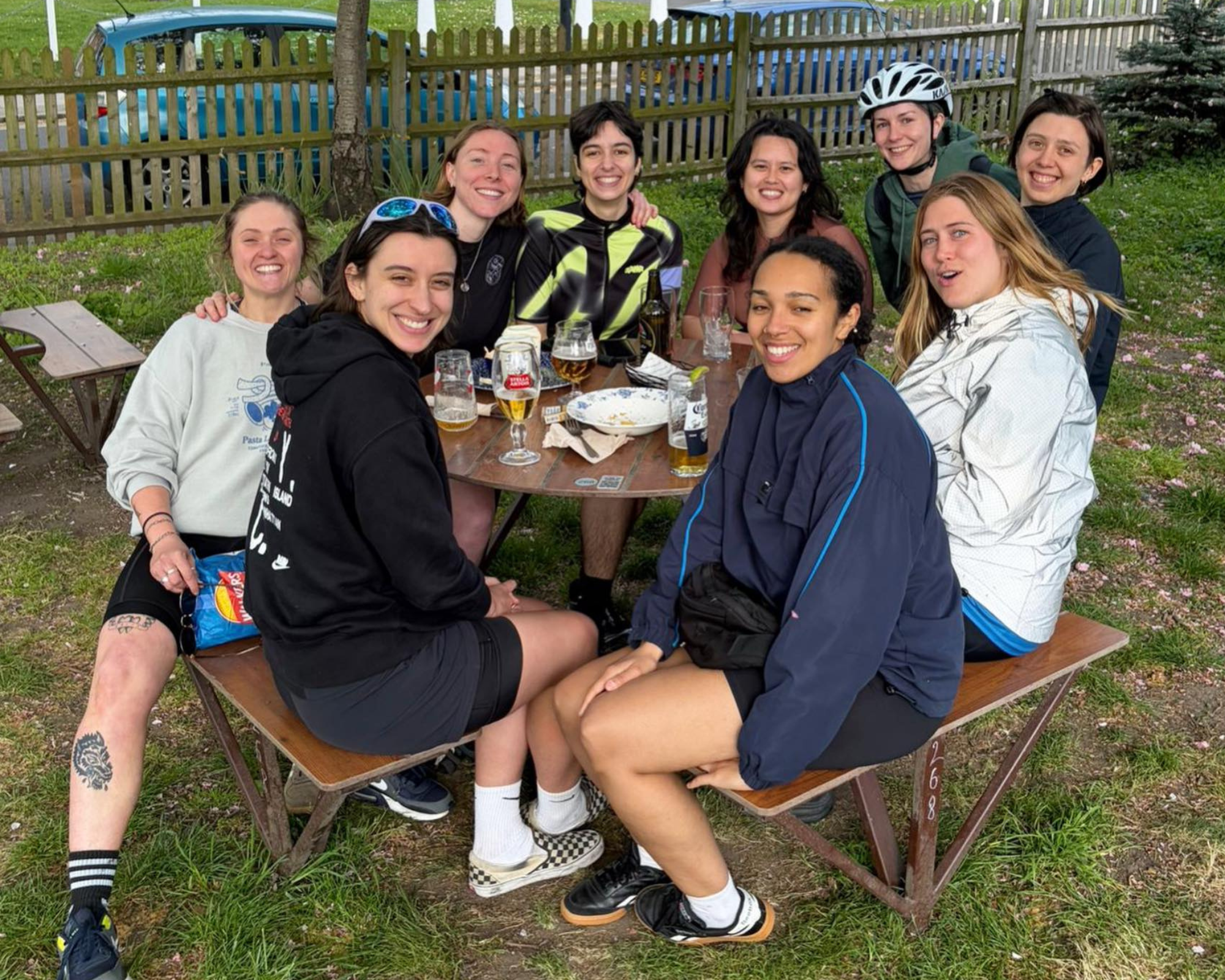 Bike Dykes group photo - sat outside on a bench in sports clothes, with one person wearing a cycling helmet.