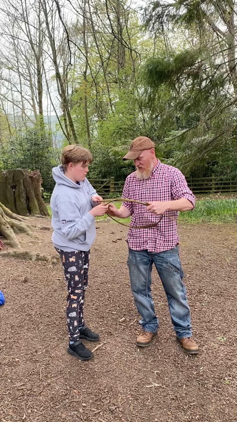 Pip wraps some willow into a circle with support from a facilitator
