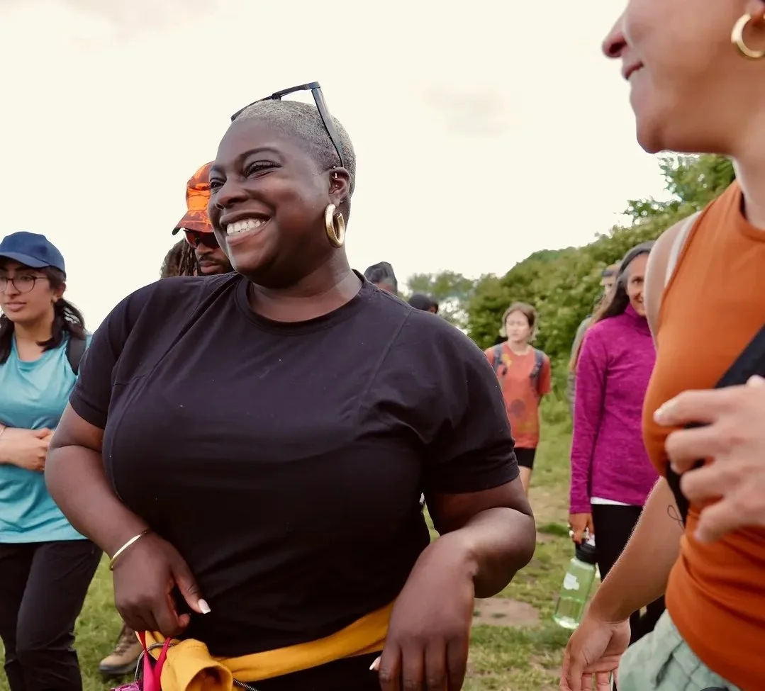 Monique is female, Black, Short hair, dark brown eyes. In this photo she is smiling at something just off camera