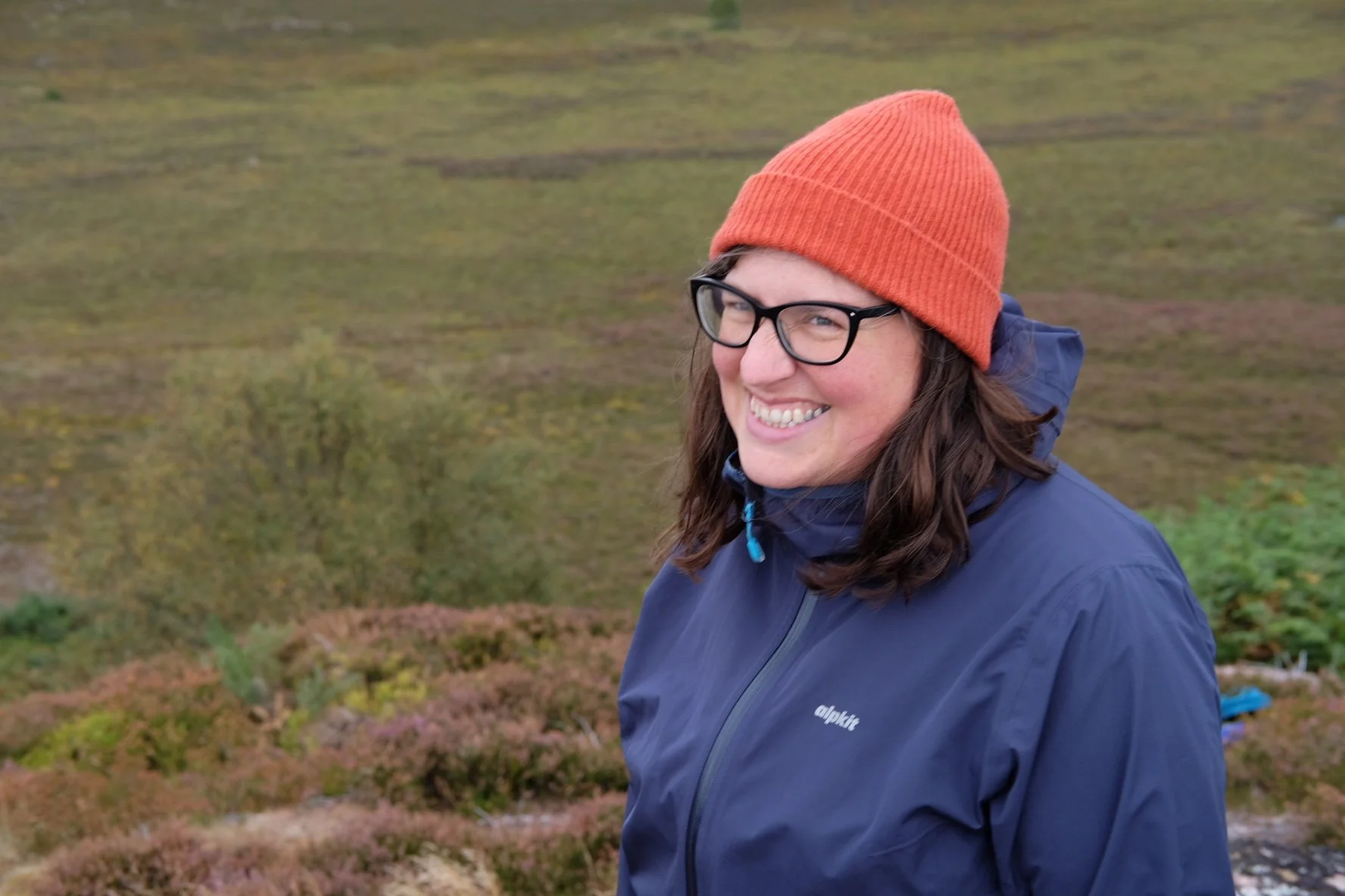 Steph is a plus size woman with wavy hair and glasses.