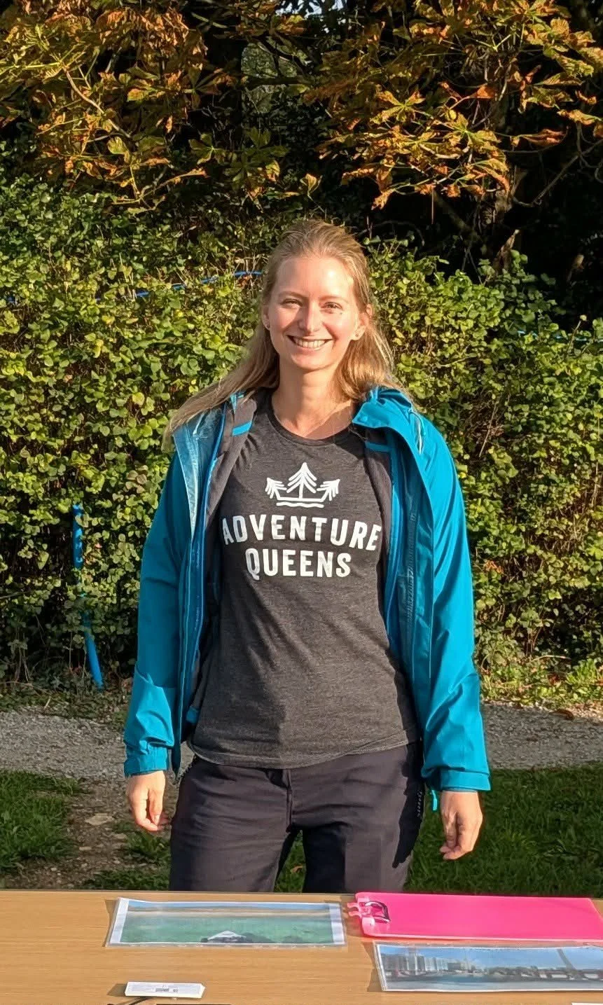 Nadia is a white woman in her late 30s, around 5ft 4, with blonde hair and blue eyes. In this photo she smiles at the camera in an Adventure Queens t-shirt