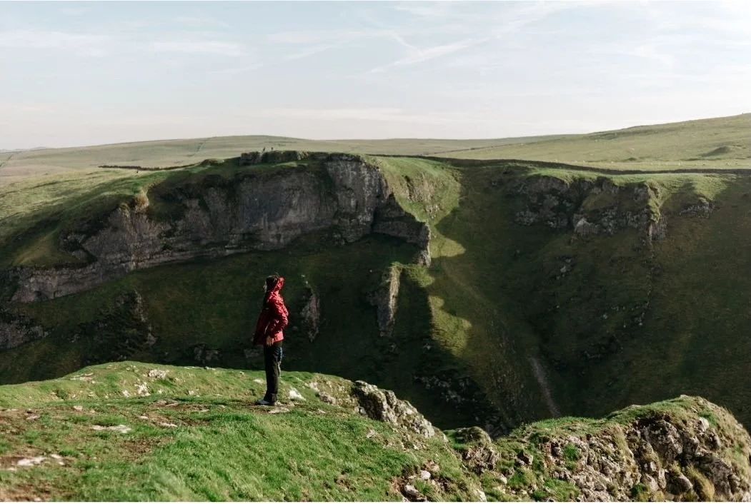 Someone stood in the mountains looking out, in a bright red coat