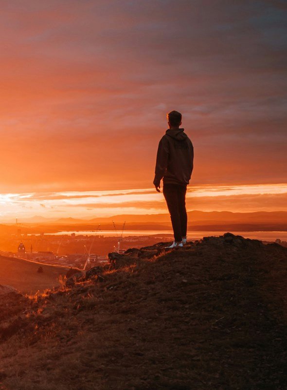 a man at sunset looking down below