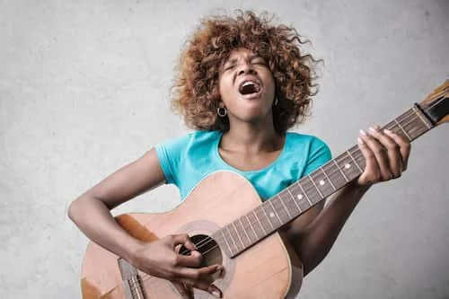 Woman passionately playing guitar and singing, performing