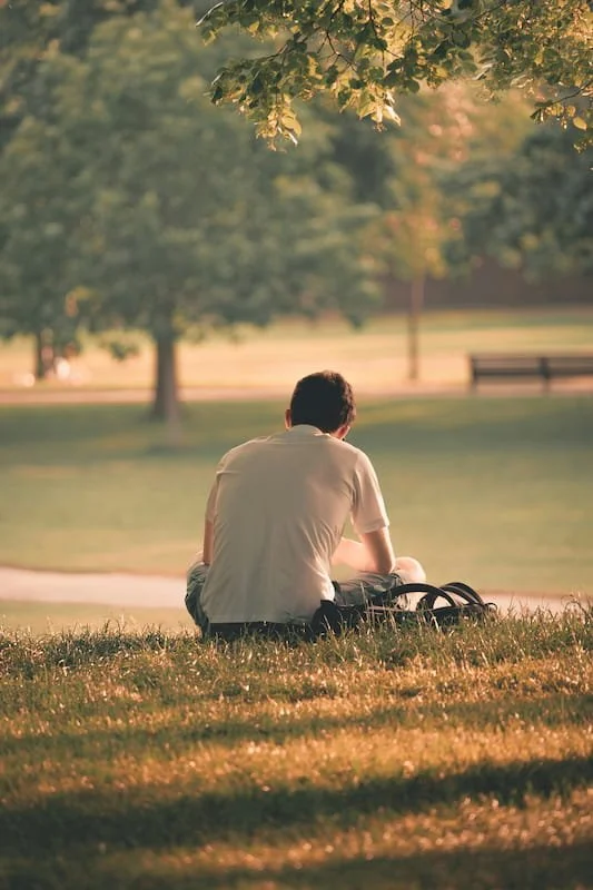 a man sitting on the ground in a park