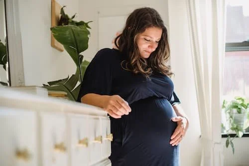 Woman pregnant and gazing at her belly with light around her