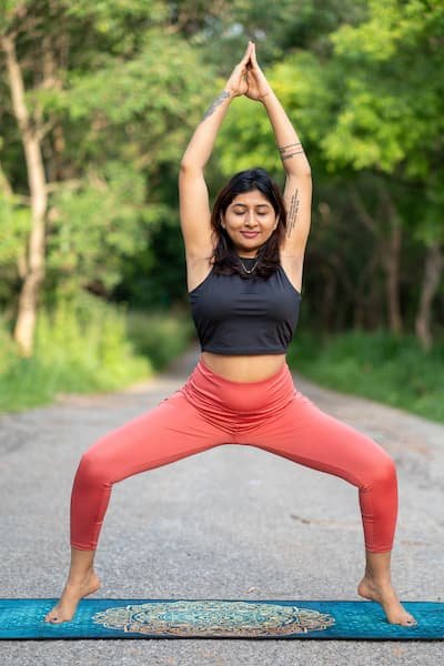 Woman feeling joyful holding a goddess pose practicing yoga outside