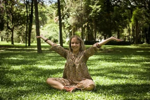 Woman smiling and holding power pose with her arms held high in the air, confident
