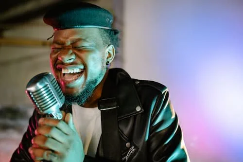 Joyful singer opening mouth with passion singing into a microphone using his voice