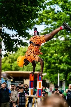 Man in deep focus balancing upside down on blocks with colorful clothing and a crowd of people watchinc