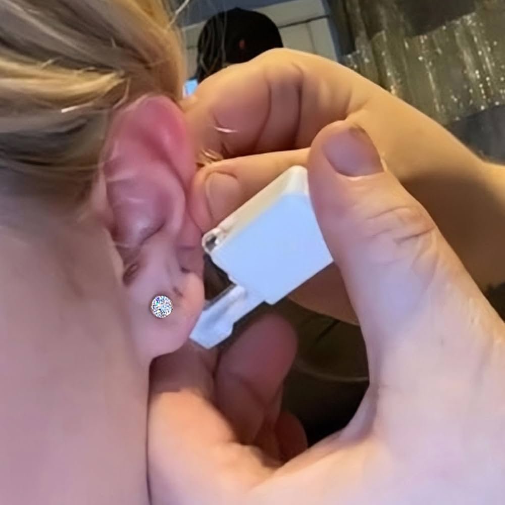 A person with short blonde hair and stud earrings lighting a cigarette with a lighter.