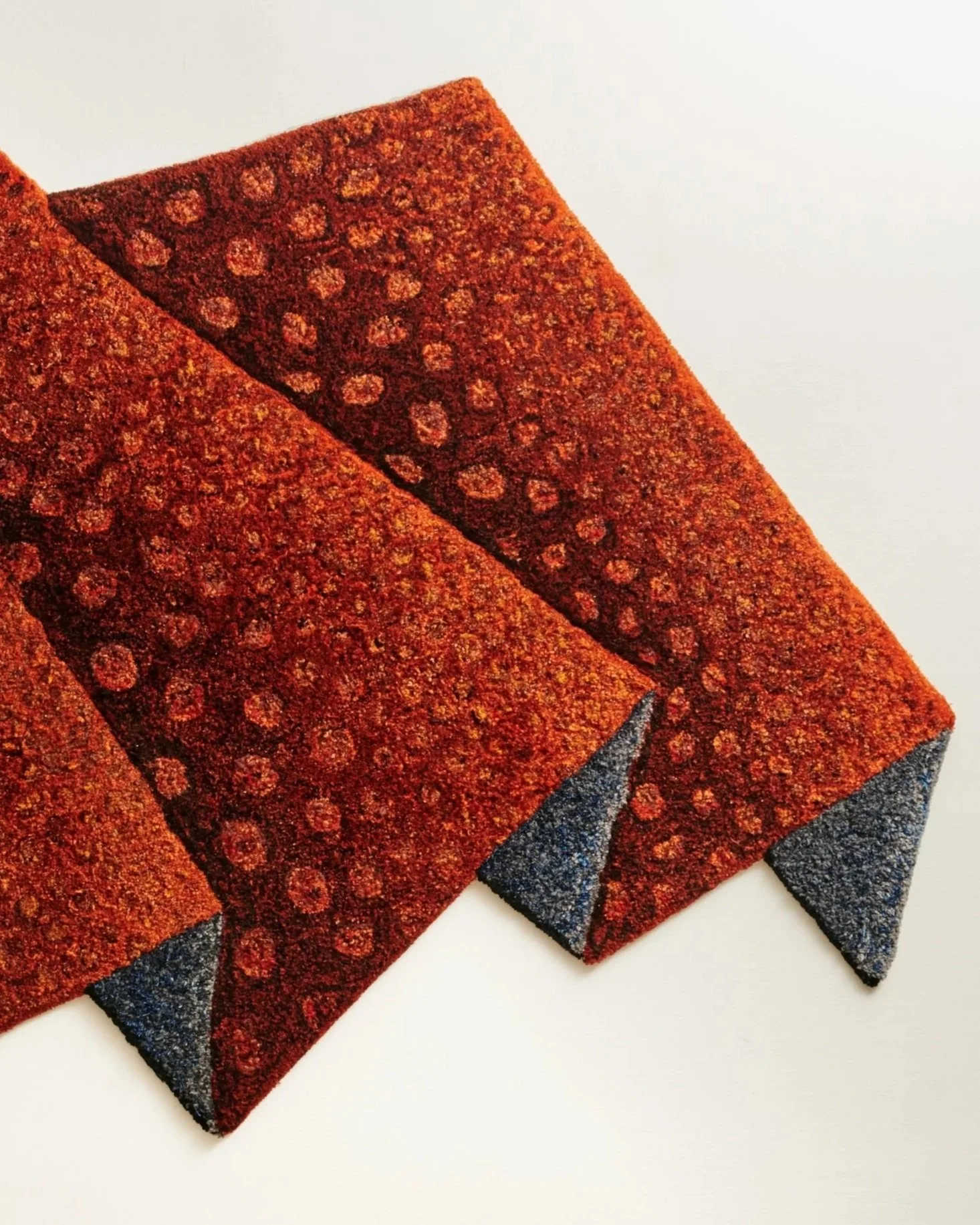 Close-up of a red and black patterned cat scratcher with textured surface and curled corners.