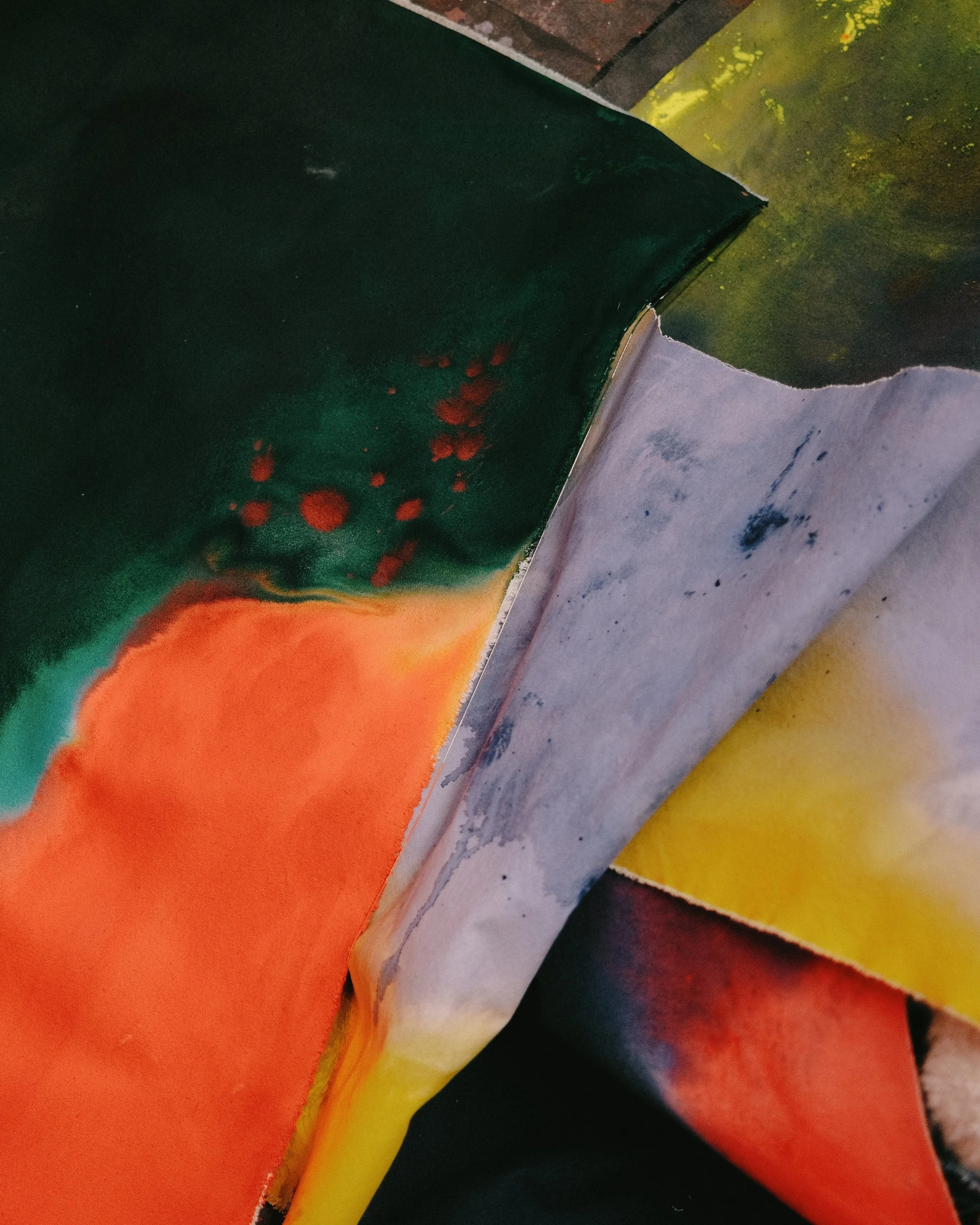 Close-up of the corner of a colorful abstract painting with orange, yellow, green, black, and white sections and textured brushstrokes. Vaughn Davis Jr.